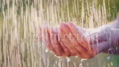 一个人握着他的手在倾盆大雨中，水滴分开。 清凉和清洁水的概念